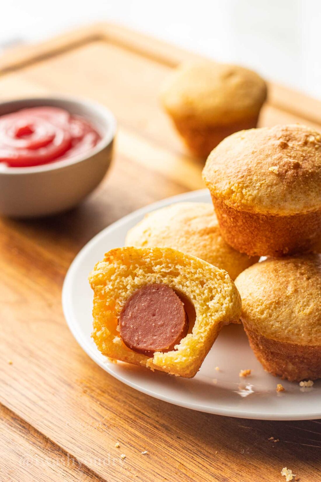 white plate with mini corn dog nuggets and a side of ketchup.