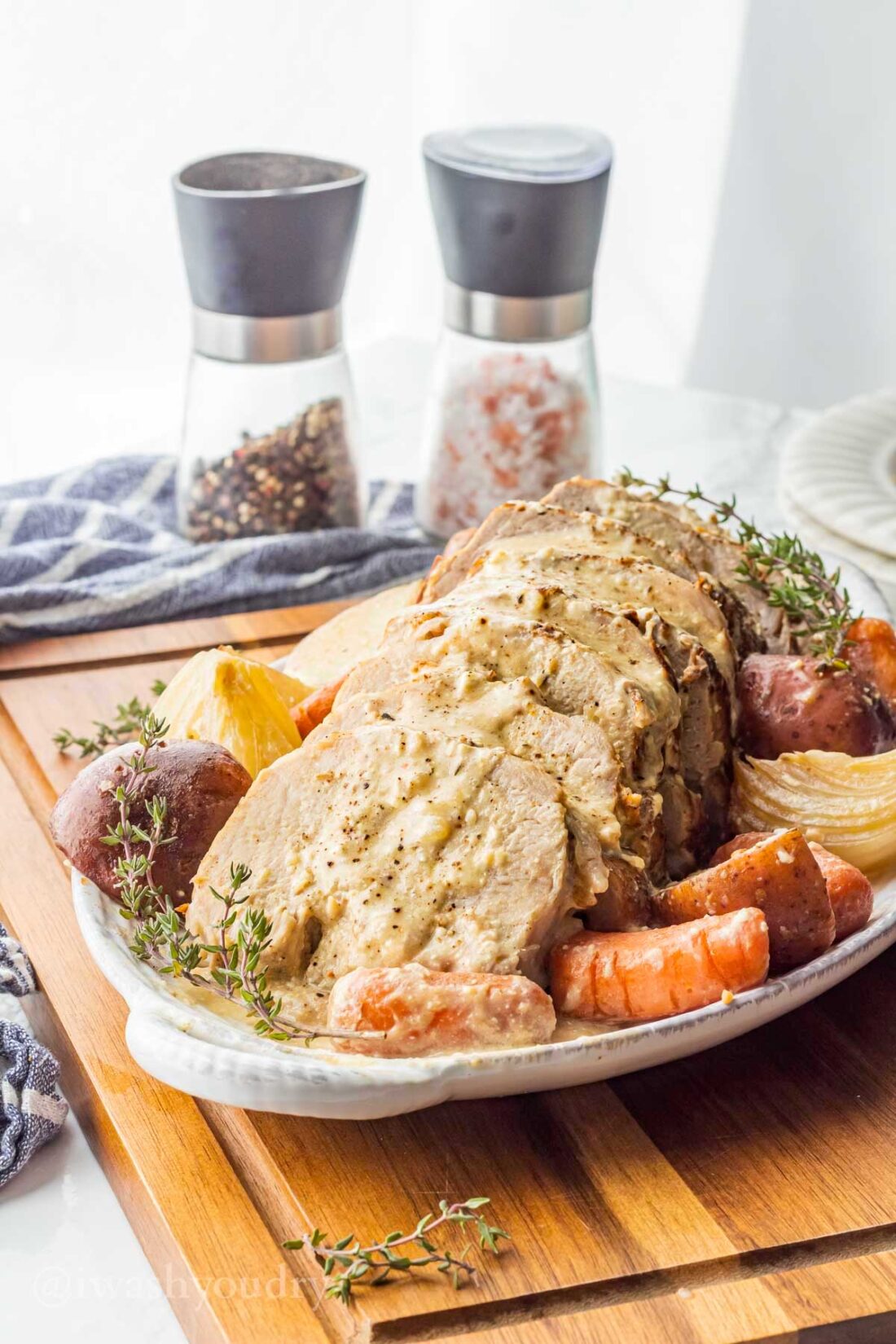 white pan with creamy garlic pot roast, potatoes and carrots in sauce.