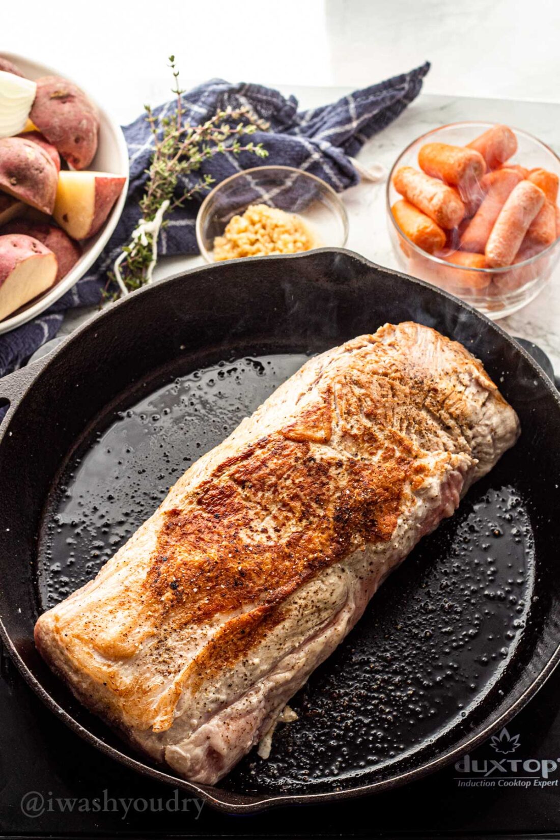 seared pork roast in cast iron skillet with salt and pepper.