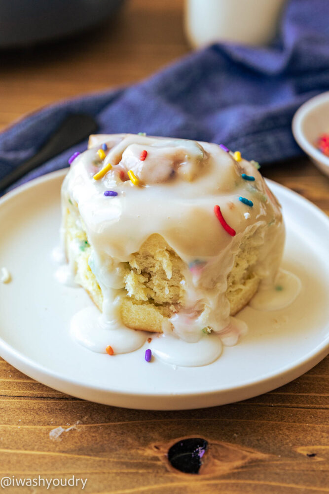 cinnamon roll on plate with sprinkles.