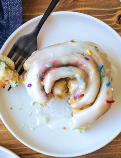 white plate with cinnamon roll and sprinkles