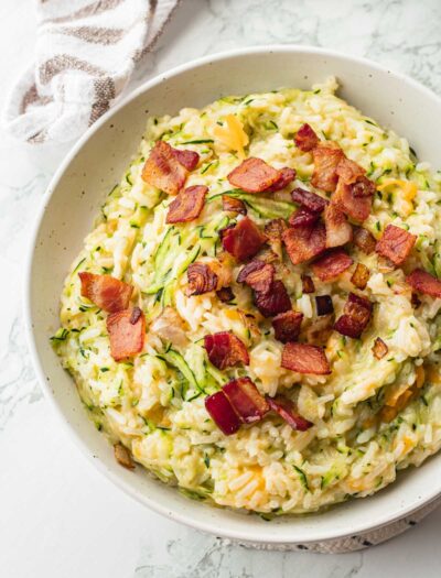 Bowl of cheesy zucchini rice with bacon.