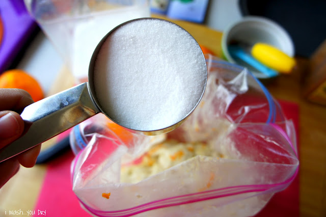 A hand holding a measuring cup of sugarer dough in a bag