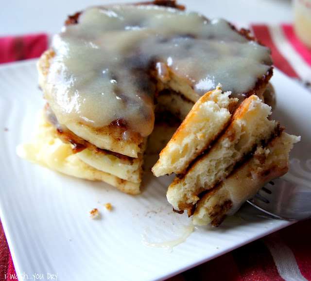 A close up of a stack of pancakes on a plate with a slice taken from the stack and displayed next to it on a fork.