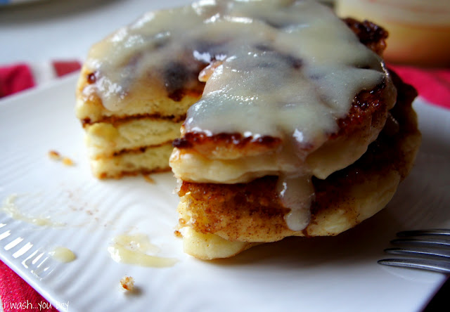 A close up of a stack of pancakes on a plate with a slice taken from it. 