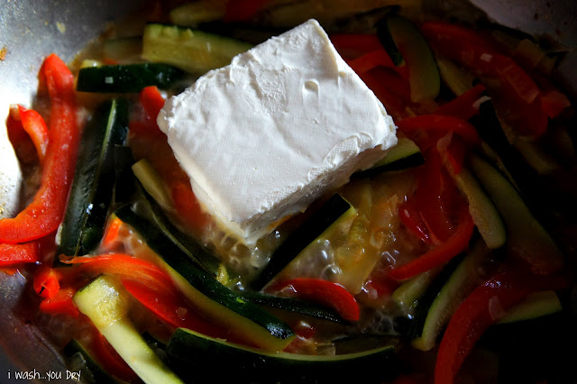 Cream cheese being added to a pan of veggies.