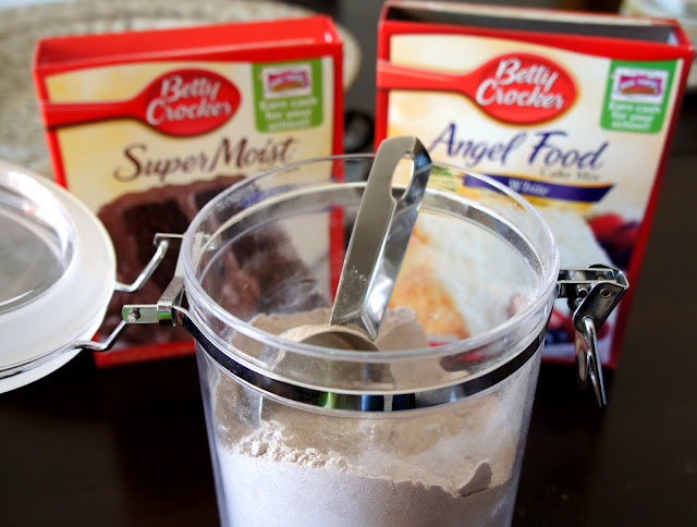 a close up of ingredients: a container of flour in the front and two boxes of cake mix behind it.