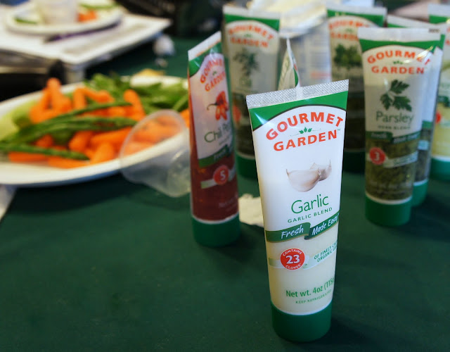 Bottles of Gourmet Garden herbs on a table next took prepared food