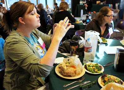 A woman taking pictures of her food while attending Camp Blogaway 2012