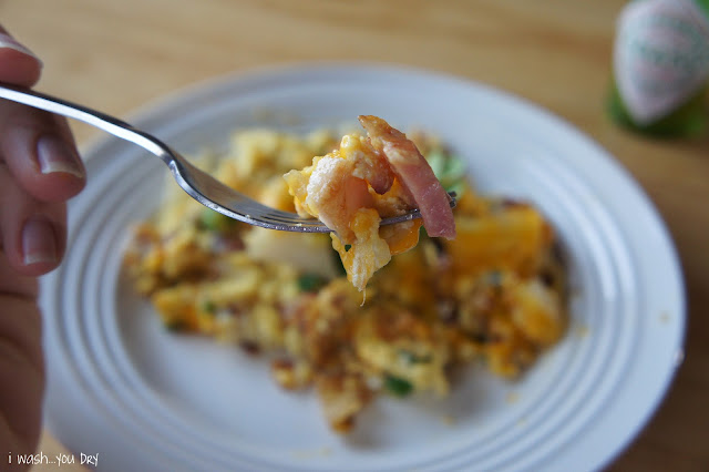 A close up of a fork with with food on it above a plate of food.