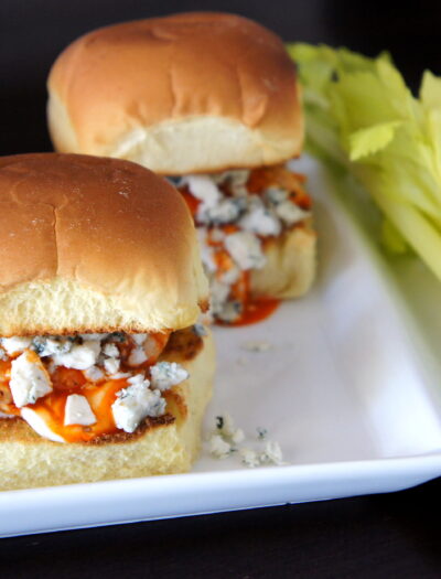 A close up of a plate of sliders filled with buffalo chicken and blue cheese