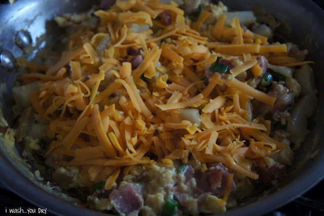 Close up of a pan of cooked food with shredded cheddar cheese on top.