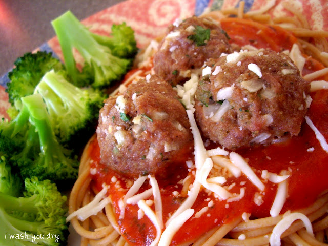 A close up of a plate of food with broccoli, meatballs and pasta. 