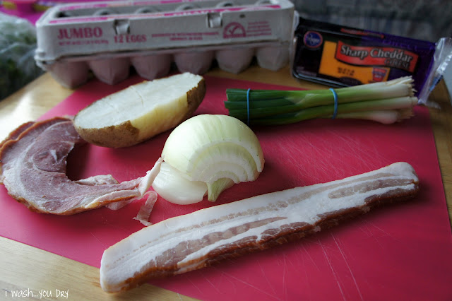 Leftovers displayed on cutting board: eggs, potato, onion, bacon, cheese and green onions. 