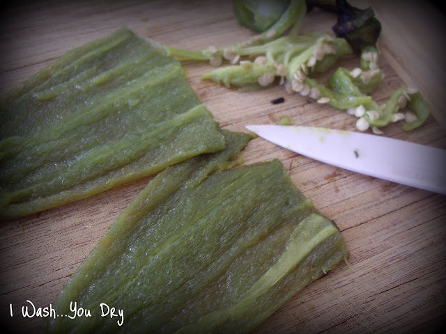 Two Jalapeños on a cutting board sliced open and seeds removed.