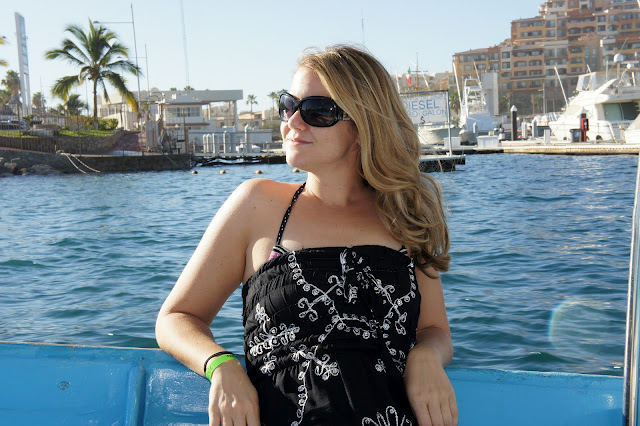 A woman with sunglasses on standing in front of a body of water