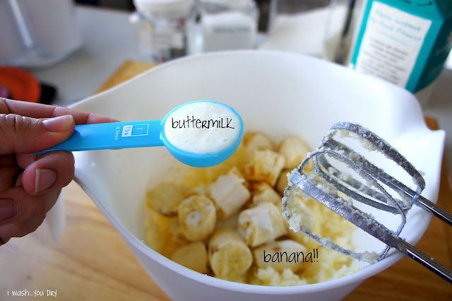 Buttermilk being added to a mixing bowl with sliced bananas in it.