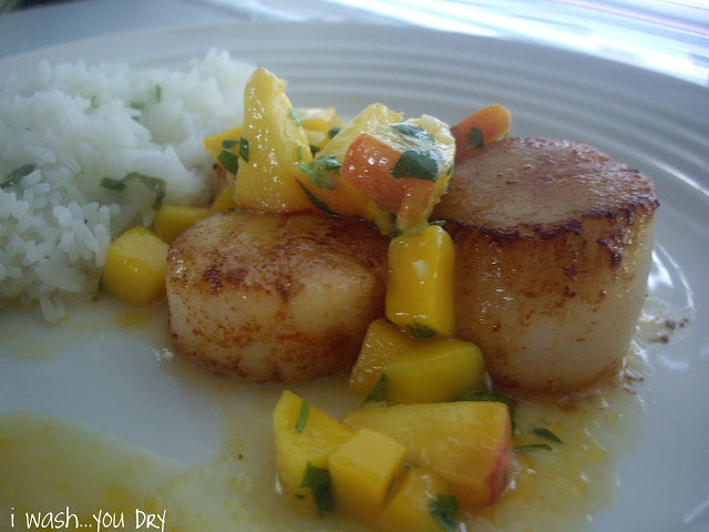 A plate displaying fried scallops topped with mango and peach salsa next to a side of rice. 