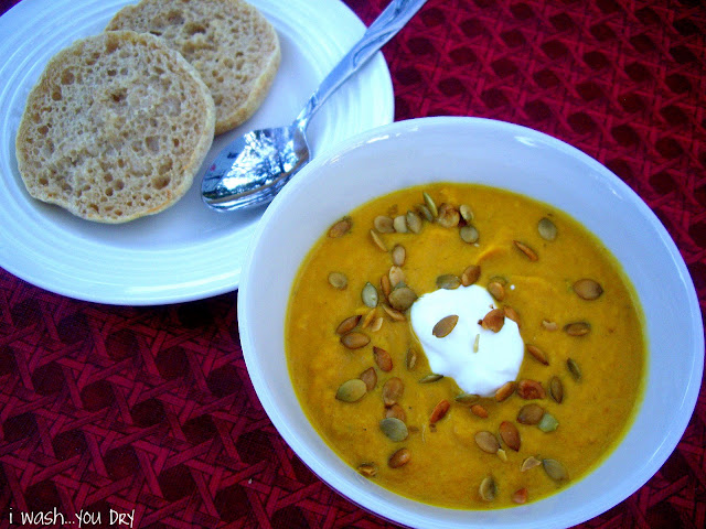 A bowl of soup next to a plate with a side of bread 