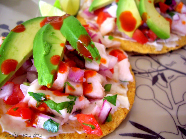 Slices of avocado on top meat and veggies on a tostada shell.