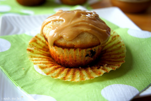 A close up of a muffin topped with a glaze with the cupcake wrapper removed from the sides. 