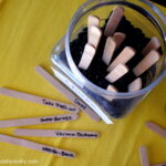 A look down on popsicle sticks with jobs on them next to a jar with stick poking out of it