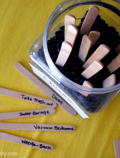 A look down on popsicle sticks with jobs on them next to a jar with stick poking out of it