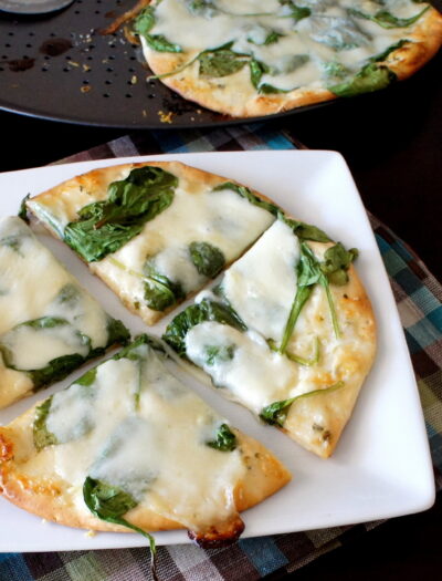 A sliced baked white pita pizza displayed on a plate