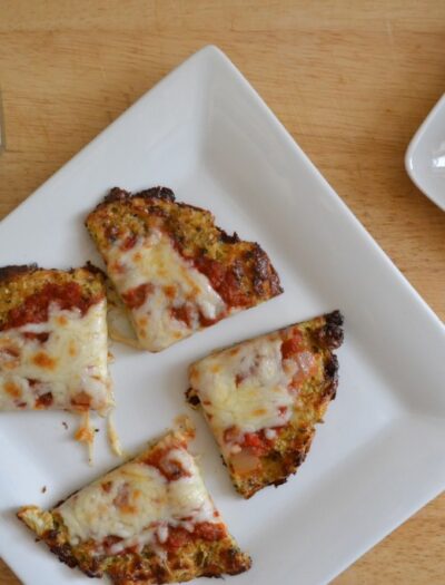 A plate with a sliced Cauliflower Crusted Pizza on it.