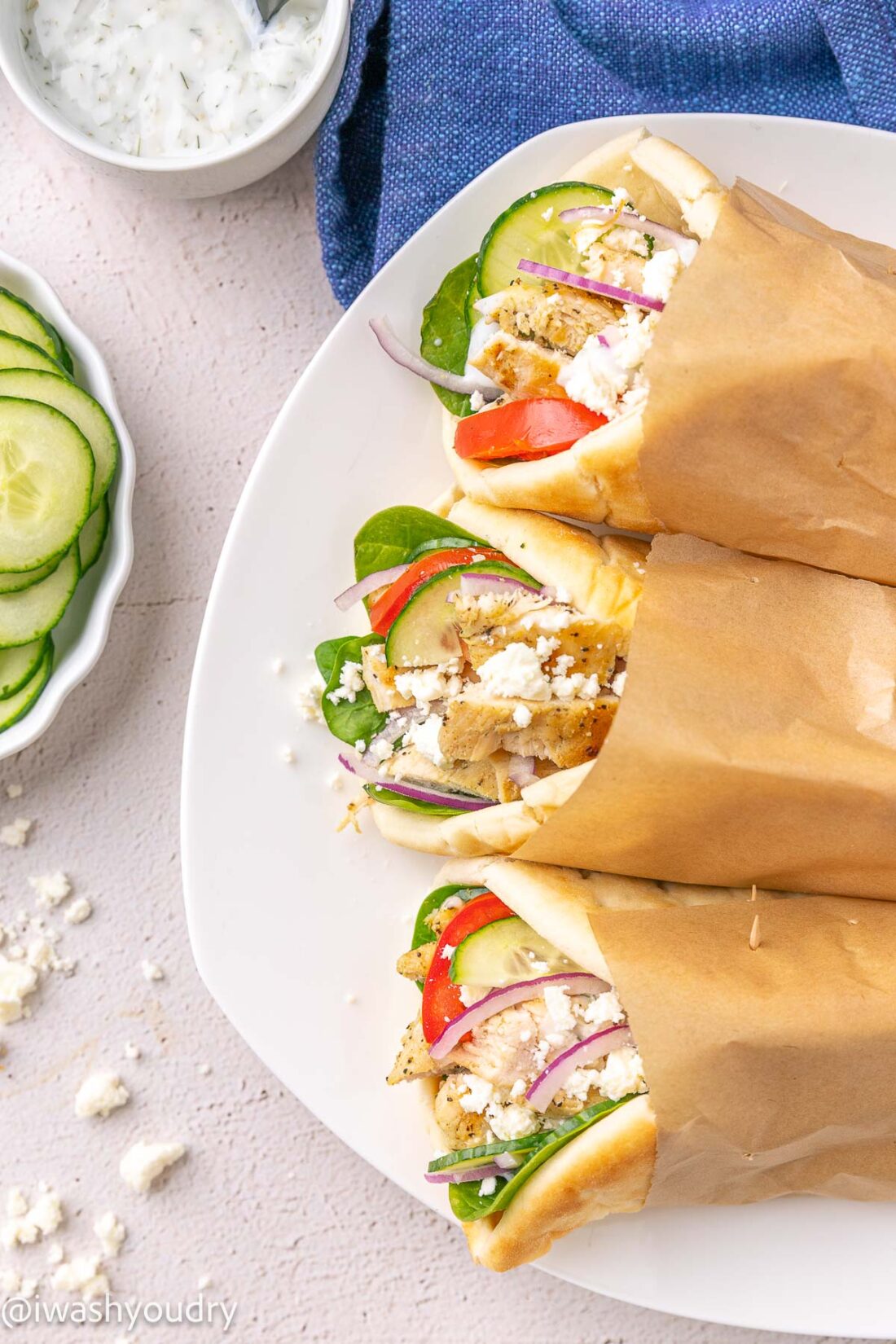 white plate with chicken souvlaki wrapped in pita bread with cucumbers.