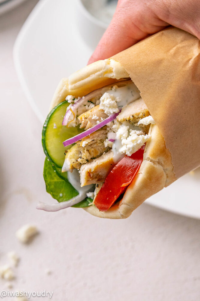 holding chicken pita sandwich with hand.