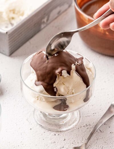 Bowl of vanilla ice cream with chocolate shell on top.