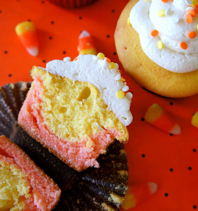 A candy corn styled cupcake sliced in half, displayed next to other candy corn cupcakes