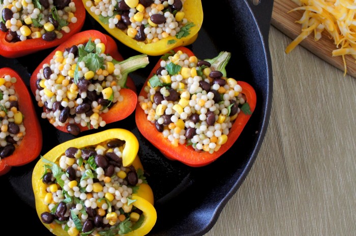 A close up of the peppers stuffed with couscous, and beans in a skillet