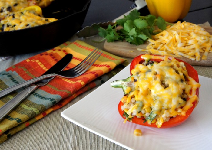 A stuffed bell pepper covered with melted cheese on a plate displayed on a table