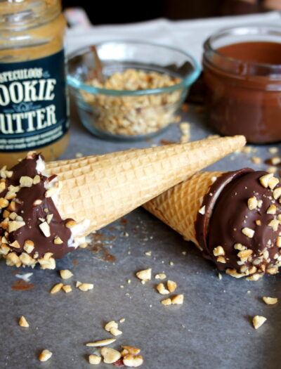 Two Homemade Cookie Butter Drumsticks displayed on a pan in front of the the ingredients needed to make it