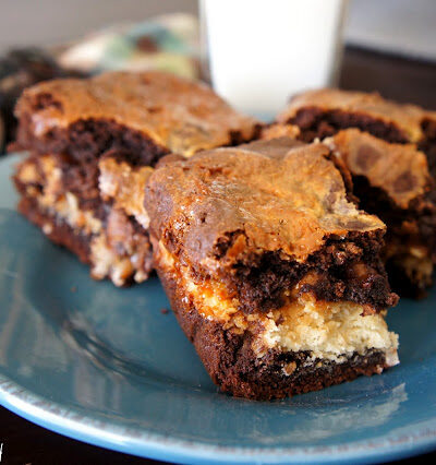 Three brownie squares on a plate next to a glass of milk