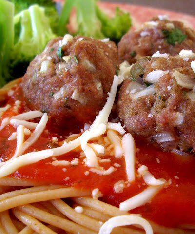 Meatballs on top of spaghetti noodles and a red sauce with side of broccoli.