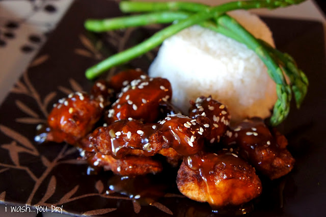 Sesame Chicken on plate next to a side of rice and asparagus sticks