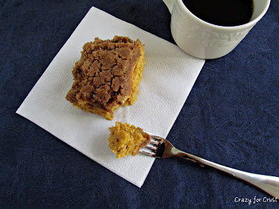 A piece of Pumpkin Coffee Cake on a napkin with a fork next to it with a bite of the cake on it. 