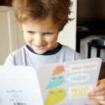 A little boy smiling holding a card