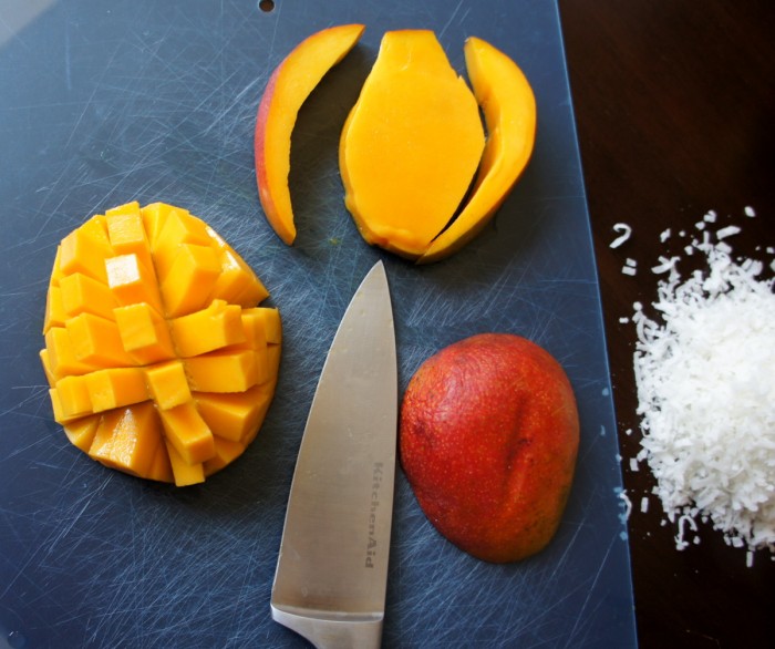 Mango sliced on a cutting board with a knife