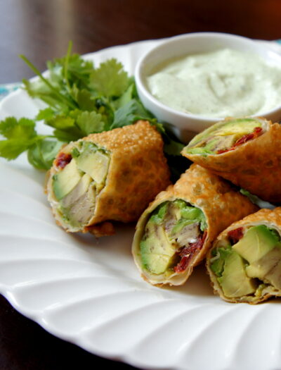 Veggie egg rolls cut in half with a side of dip