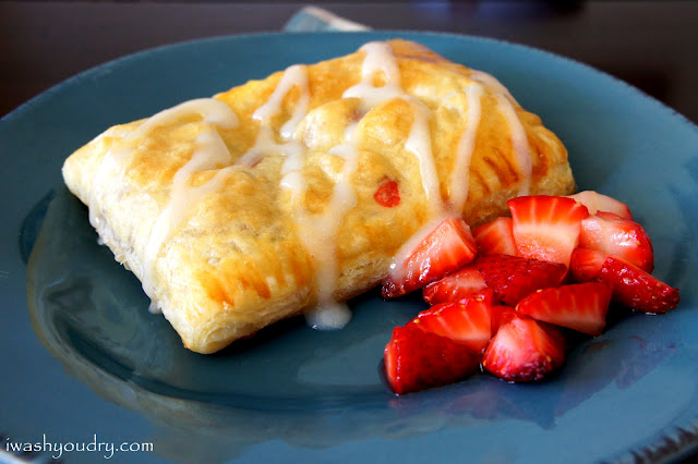 A plate with a Strawberry & Cream Cheese Toaster Strudels and a side of chopped strawberries