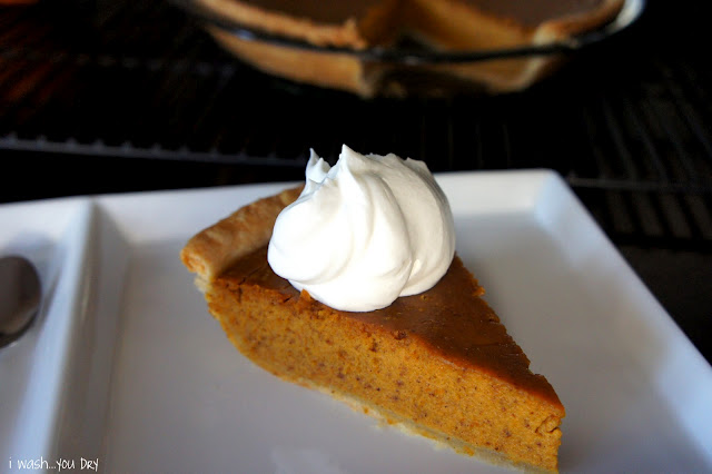 A slice of pumpkin pie on a plate with whipped cream on top