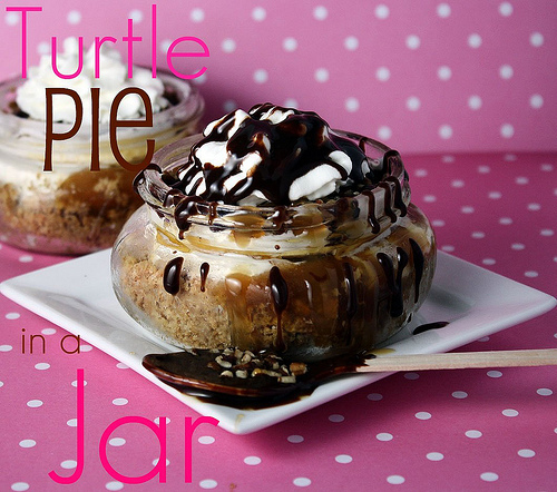 Frozen Turtle pie in a small mason jar topped with drizzled chocolate topping on a white square plate