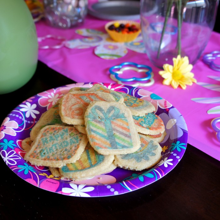 A plate of sugar cookies on a party plate surrounded by party birthday table decor