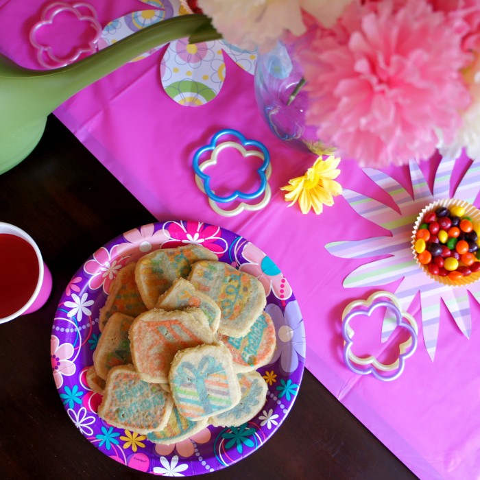 A look down on a plate of sugar cookies on a party plate surrounded by party birthday table decor