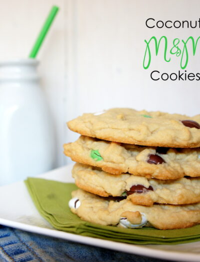 Four Coconut M&M Cookies stacked on top of each other on a plate