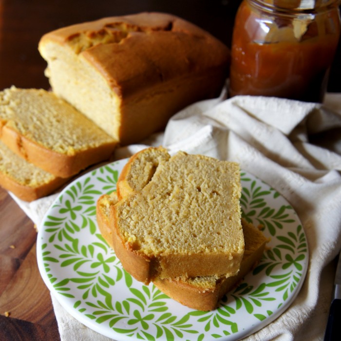 Two sliced of pound cake on a plate in front of the loaf they were sliced from